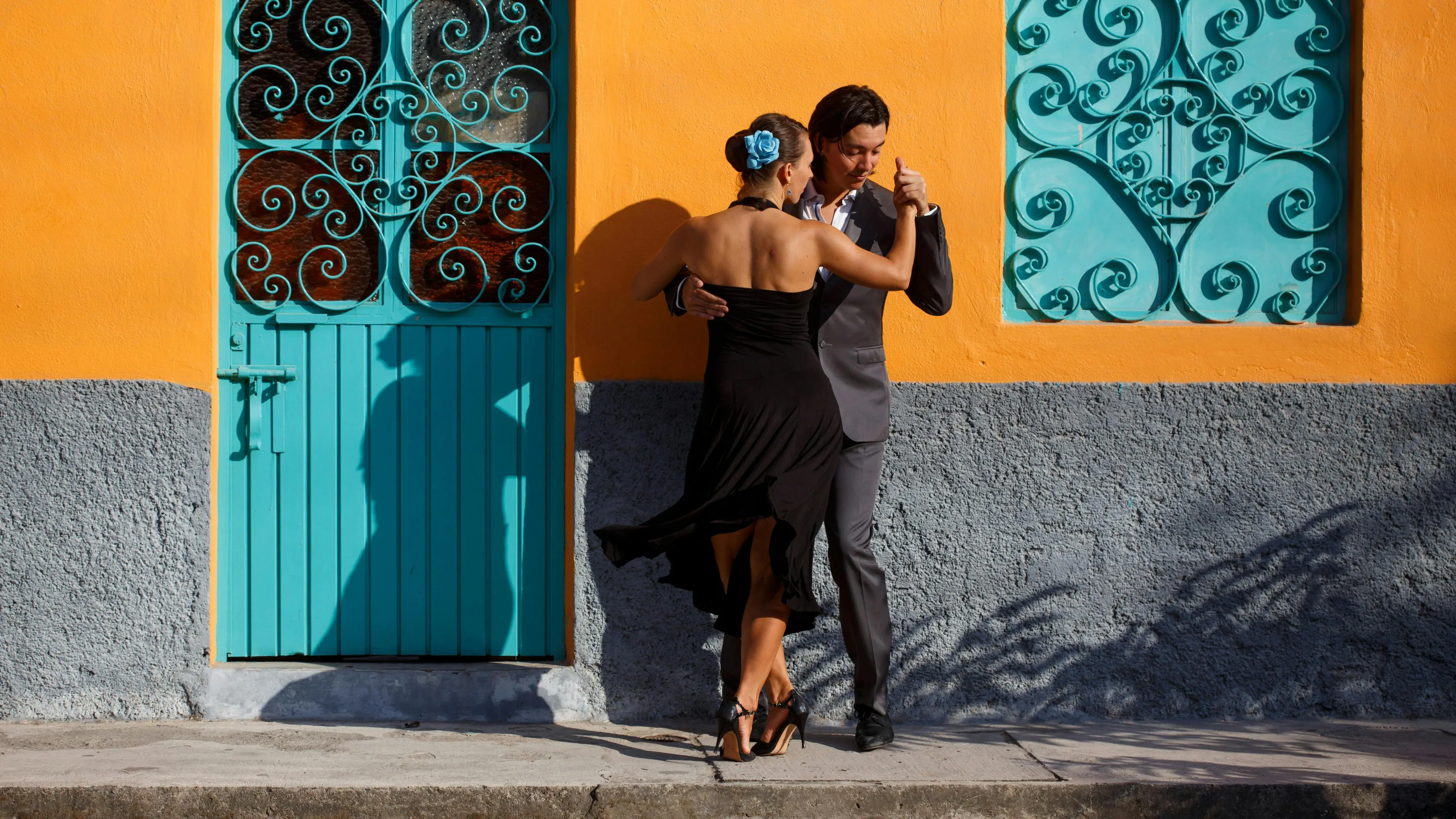 Clase individual de bachata en una academia pequeña, con el instructor y el alumno reflejados en los espejos